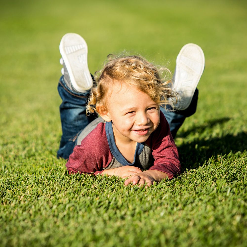 Barn smiler og nyder livet på friskt, grønt græs